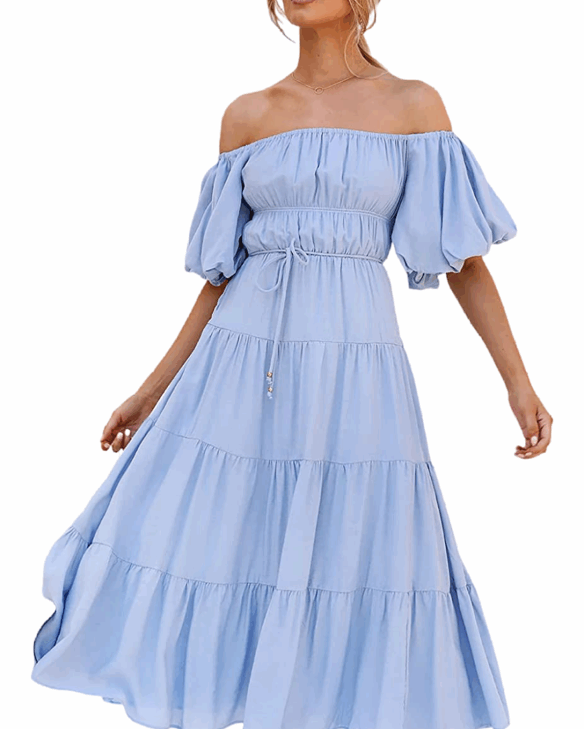 A woman wearing a light blue, off-the-shoulder, tiered maxi dress with puffed short sleeves and a cinched waist, standing against a white background.