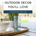 A wooden tray with stacked white bowls, plates, and glass cups sits on an outdoor table next to a potted plant; text reads "Affordable Outdoor Decor You'll Love.