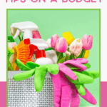 A white basket holds cleaning supplies, rubber gloves, and pink tulips against a green background. Text above reads, "Spring Cleaning Tips on a Budget.