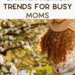 A woman with curly hair in a floral dress holds a hat in a blooming garden. Text reads: "Spring Fashion Trends for Busy Moms.