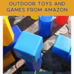 Large colorful plastic blocks are scattered on a patterned mat beside bright outdoor planters. Text on the image reads, "Must-have outdoor toys and games from Amazon." A button at the bottom says, "read more.
