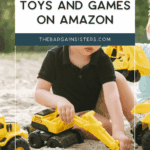 A young child sits outdoors playing with yellow toy construction vehicles in sand, surrounded by outdoor planters. Text above reads: "Top Outdoor Toys and Games on Amazon. thebargainsisters.com.