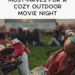 People sitting on lawn chairs with blankets and snacks, watching an outdoor movie at dusk. Outdoor planters frame the cozy scene, with a large screen in the background and a relaxed, inviting atmosphere. Text above reads, "Must-haves for a cozy outdoor movie night.