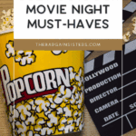 A tipped-over popcorn bucket spilling popcorn next to a movie clapperboard and stylish outdoor planters on a wooden surface, with text that reads, "Cozy Outdoor Movie Night Must-Haves.