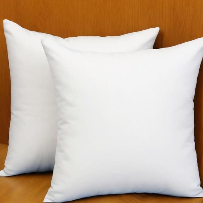 Two plain white square pillows are placed upright on a wooden surface against a wooden background. Soft, clean, and plump, they invite comfort—perfect for refreshing your space with this week’s exclusive Monday Deals.
