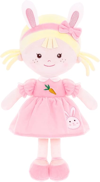 A soft plush doll with blonde hair, pink dress with a carrot and bunny, pink shoes, and bunny ear headband. The doll has a smile, rosy cheeks, a bow on its head—perfect for gifting and available now in our Monday Deals!.