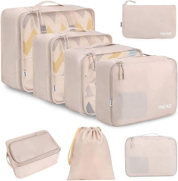 A set of beige travel packing cubes and bags of various sizes, including zippered pouches, a drawstring bag, and a small storage pouch, neatly arranged on a white background—perfect for organizing your suitcase during Tuesday Deals.