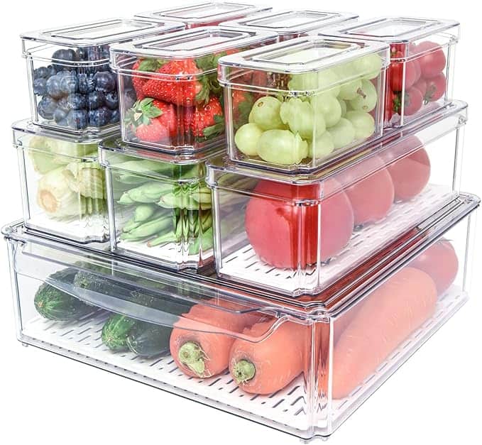 Clear plastic refrigerator storage containers neatly arranged and filled with fresh fruits and vegetables, including grapes, strawberries, tomatoes, and carrots—perfect for organizing your produce after stocking up during Thursday Deals.