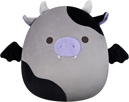 A round, plush toy shaped like a cow with gray and black patches, small horns, bat wings, a purple snout with tiny fangs, and simple brown eyes—perfect for snagging during our Monday Deals!.