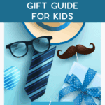 Flat lay of Father’s Day items on a blue background, including a striped tie, glasses, mustache, wrapped gift with a bow, heart, and a straw hat. Text reads: “Easy Father’s Day Gift Guide for Kids.”.