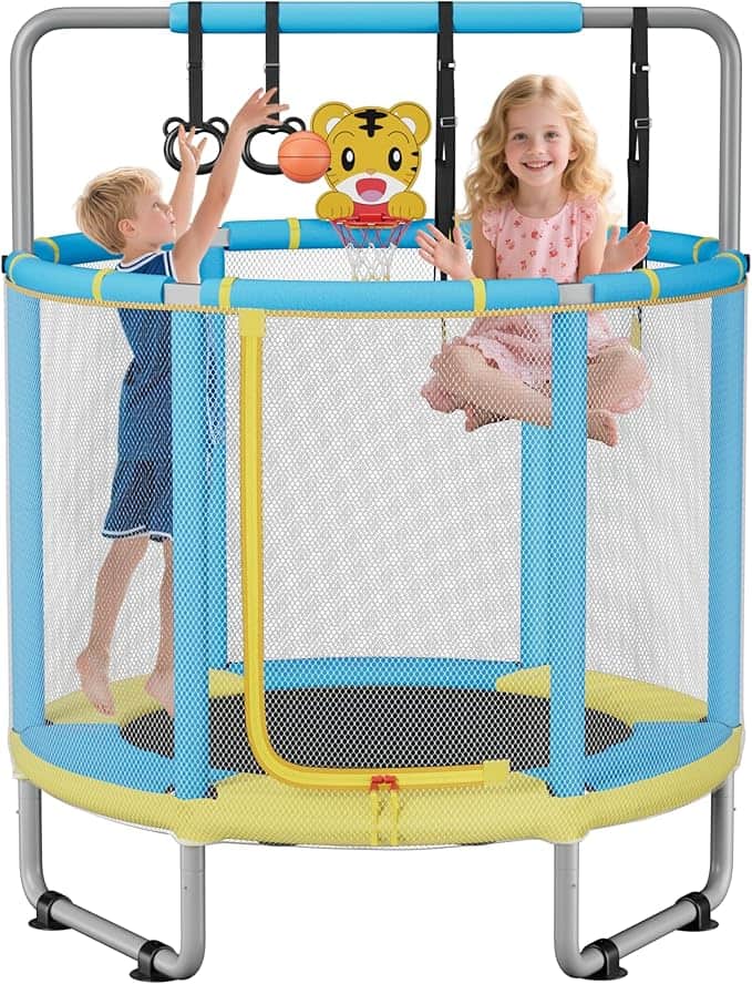 Two young children play on a small indoor trampoline with blue and yellow safety netting; one boy tries to throw a basketball into a tiger-themed hoop while a girl sits, smiling—perfect fun for little ones, especially with Tuesday Deals.