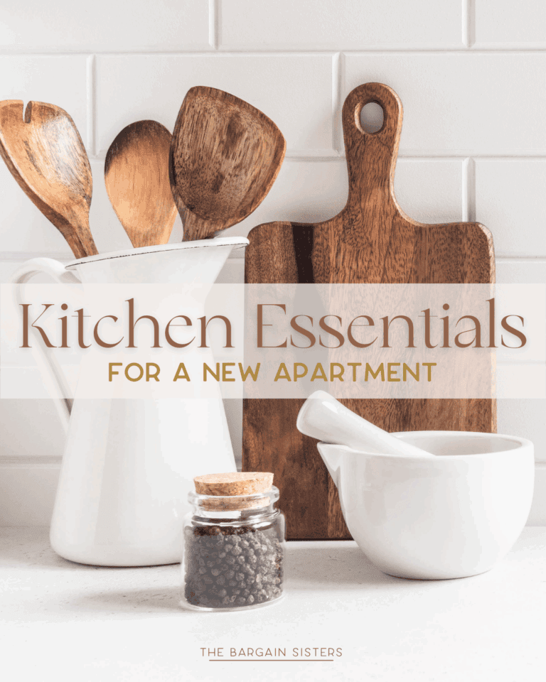 Wooden spoons in a white pitcher, a wooden cutting board, a glass jar of peppercorns, and a mortar and pestle sit on the counter with the text “Kitchen Essentials For New Apartment” – perfect for stocking up on kitchen essentials for new apartment living.
