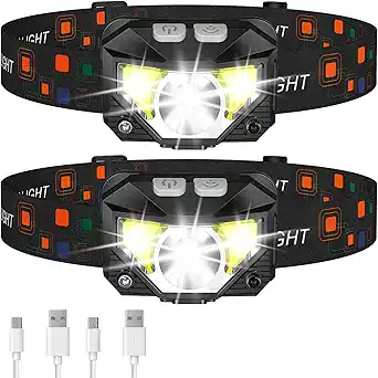 Two black LED headlamps with colorful accents on adjustable straps, both lit up brightly. Includes two USB charging cables placed below the headlamps—perfect for grabbing during Tuesday Deals.