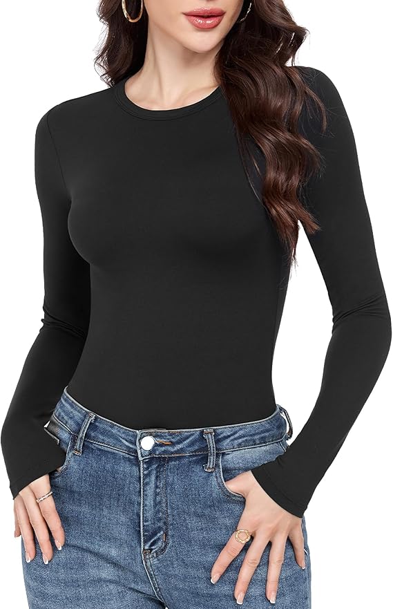 Woman wearing a fitted, long-sleeve black top and blue jeans, with hands in her pockets. She has wavy brown hair, hoop earrings, and rings. Perfect for Thursday Deals style inspiration. The background is white.