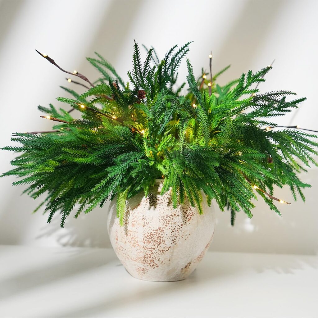 A lush green fern in a textured, white ceramic pot, decorated with small string lights, sits on a white surface with sunlight streaming in—perfect for brightening your space. Don’t miss out on exclusive Friday Deals!.