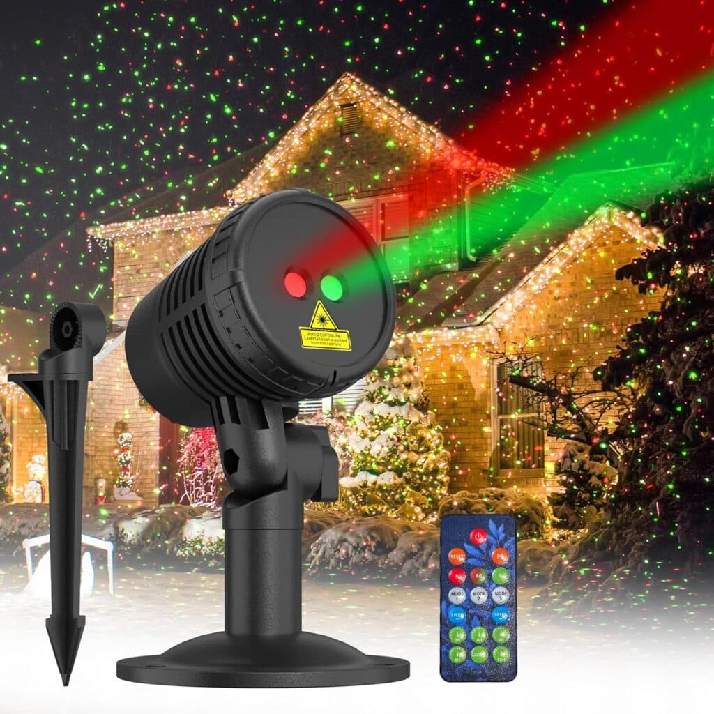 A black outdoor laser light projector emits red and green lights onto a house with festive holiday decorations. A remote control and ground stake are included—perfect for grabbing during Thursday Deals!.