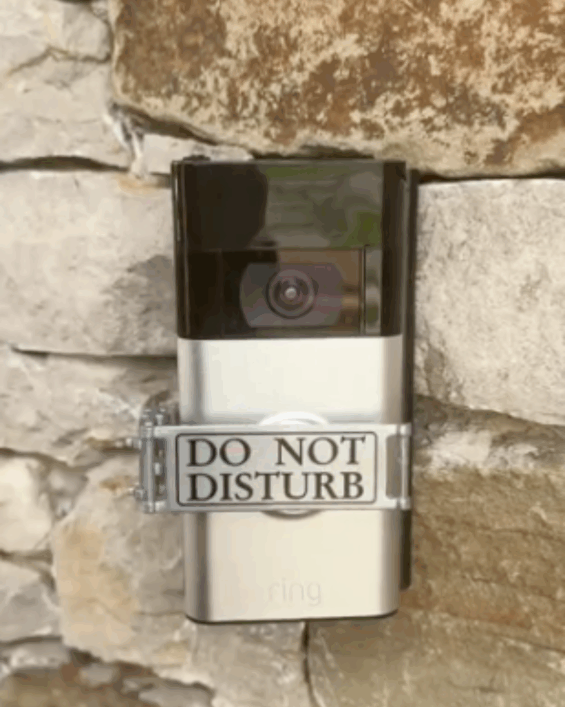 A Ring video doorbell is mounted on a stone wall with a metallic sign attached to it that reads "DO NOT DISTURB.