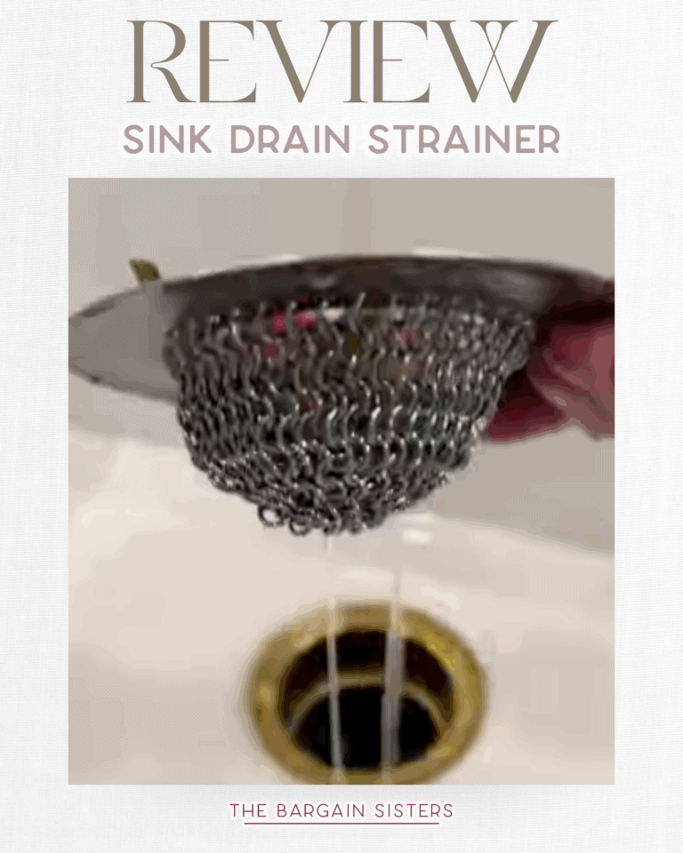 A hand holds a metal mesh sink drain strainer above a white sink with water and debris collected inside. Text above reads "REVIEW Sink Drain Strainer & Air Conditioner Cover" and below reads "THE BARGAIN SISTERS.