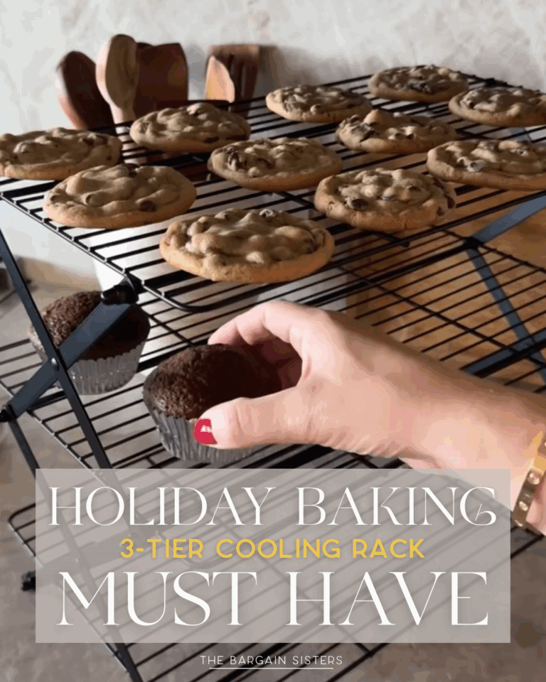 A hand places a chocolate cupcake on a 3 tier cooling rack filled with freshly baked chocolate chip cookies. Text overlay reads: "Holiday Baking 3-Tier Cooling Rack Must Have. The Bargain Sisters.