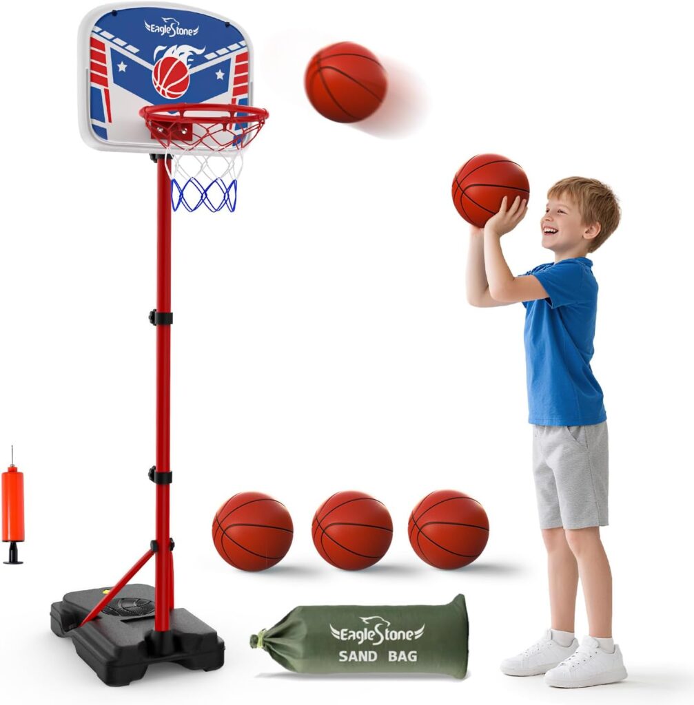 A smiling young boy in a blue shirt and gray shorts prepares to shoot a basketball at a child-sized hoop. Don’t miss out on Tuesday Deals for this fun set—basketballs, a pump, and a green sand bag are included.