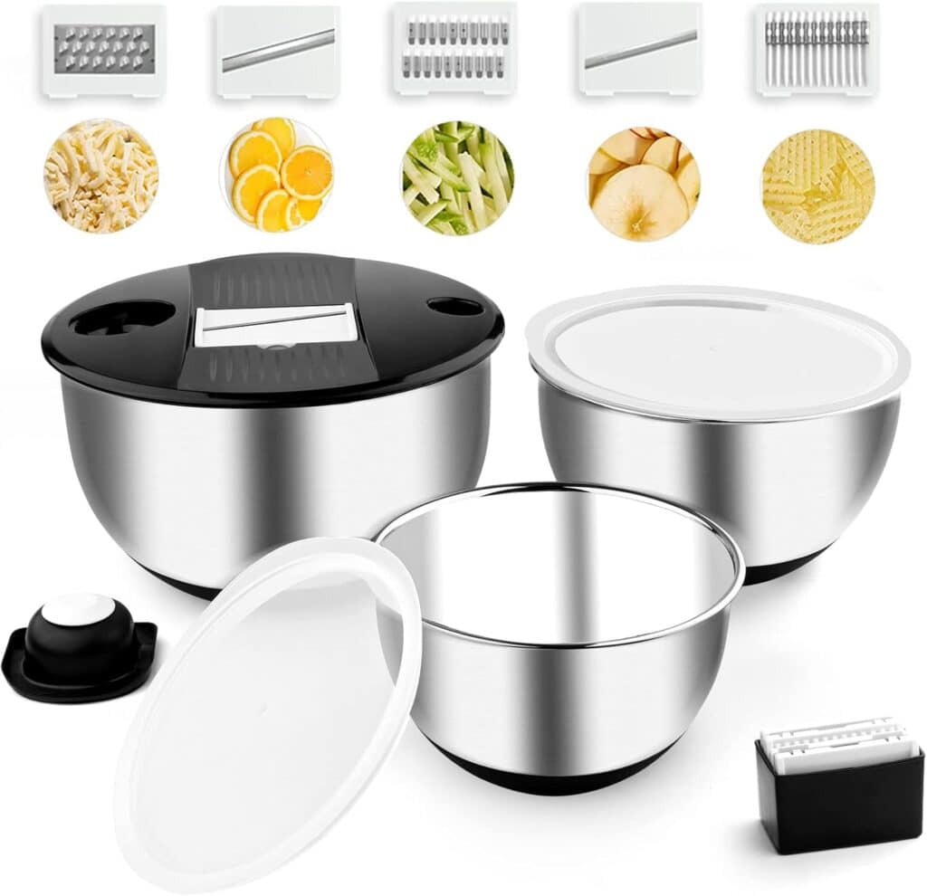 A stainless steel mixing bowl set with lids, a black and white mandoline slicer, five interchangeable grater blades, and various sliced fruit and vegetable examples shown above the bowls.