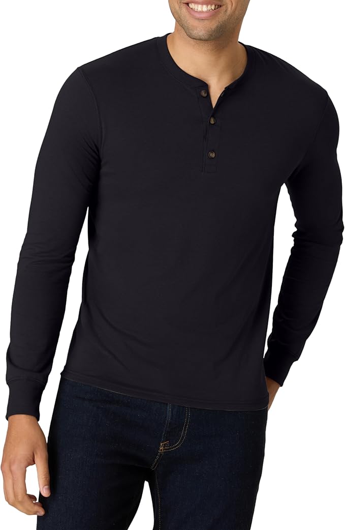 A man wearing a fitted, long-sleeve, black henley shirt with three buttons at the collar and dark jeans stands smiling with one hand in his pocket—ready for Friday Deals.