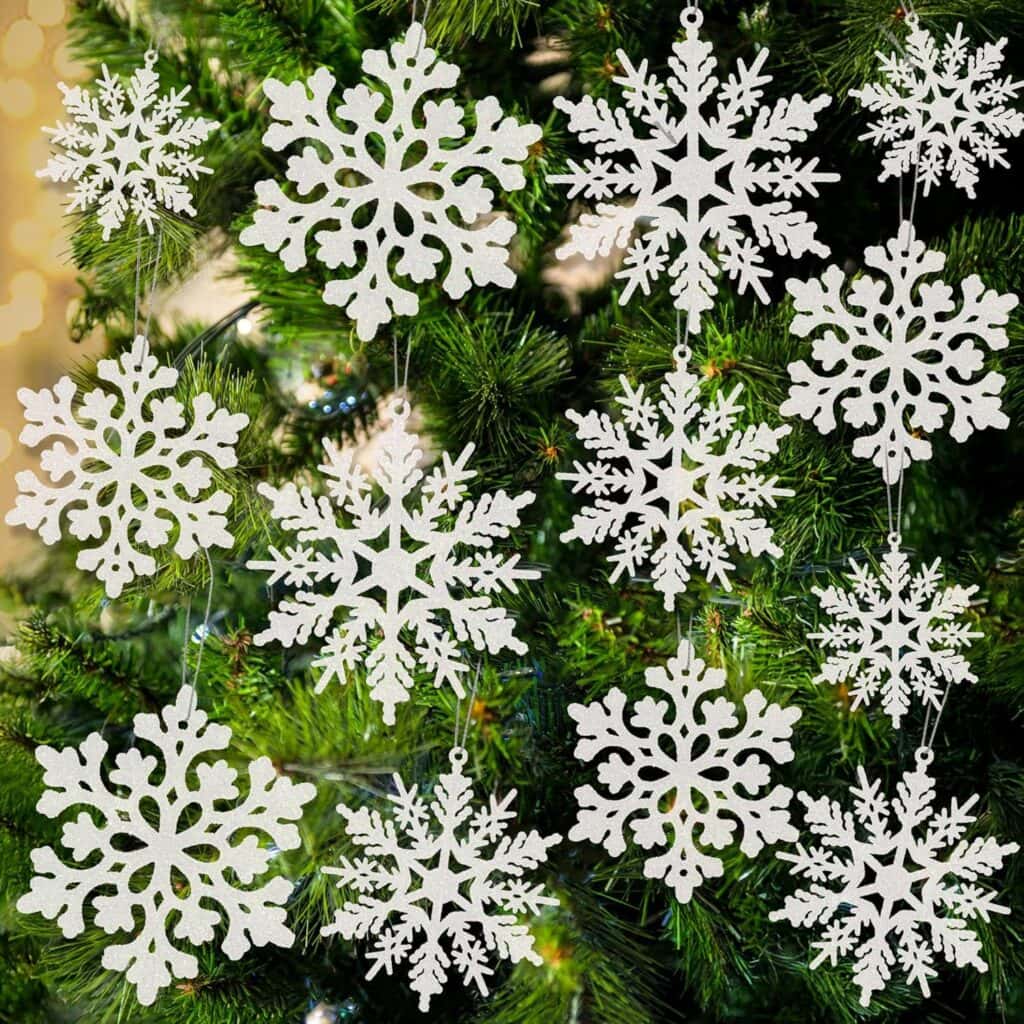 White snowflake ornaments hang on a green Christmas tree, creating a festive and wintry display. Take advantage of special Wednesday Deals to add these intricate snowflake designs to your holiday décor this season.
