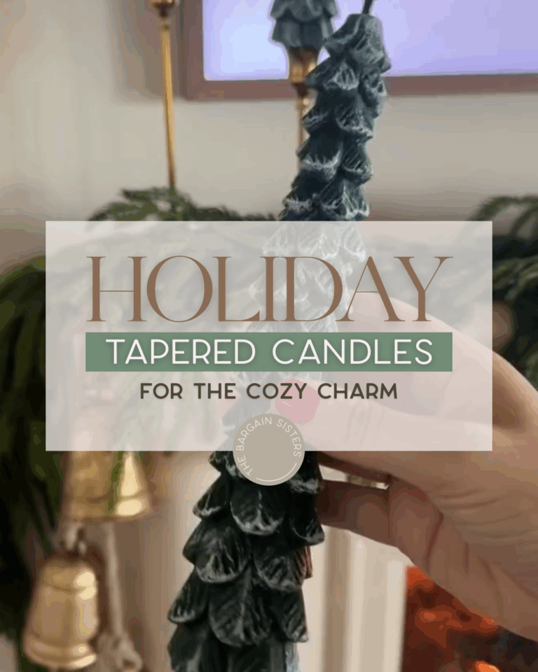 A hand holds a green, tree-shaped tapered Christmas candle in front of a festive holiday background with garland and gold bells. Text overlay reads: "Holiday Tapered Candles For The Cozy Charm.