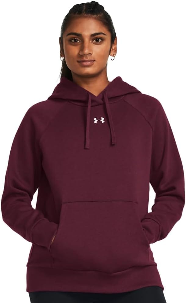 A woman wearing a maroon Under Armour hoodie with a white logo on the chest stands with her hands in the front pocket, looking forward.