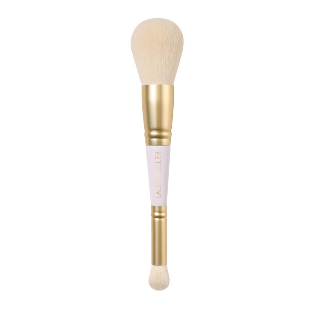 A double-ended makeup brush with gold and white handle; one end has a large, fluffy brush and the other has a smaller, rounded brush.