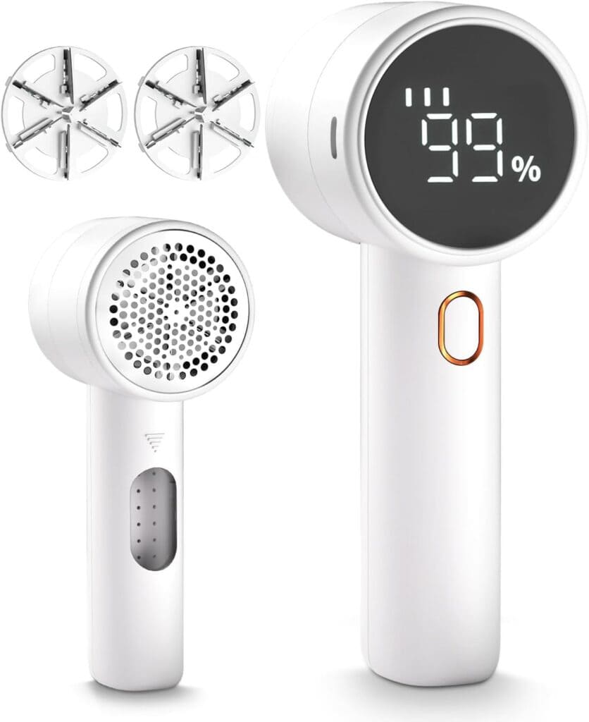White handheld fabric shaver with a digital display showing 59%, removable blade covers, and a power button. The image shows both front and back views and includes two replacement blade sets.