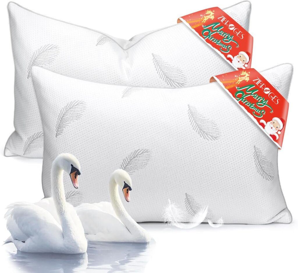 Two white pillows with feather patterns are displayed behind two swans on water. Holiday-themed tags with Santa graphics and the words "Merry Christmas" are attached to the pillows. A few white feathers float nearby.