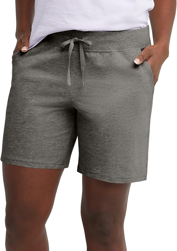 A person wearing gray drawstring shorts and a white shirt with their hands in the shorts' pockets, shown from the waist to mid-thigh.