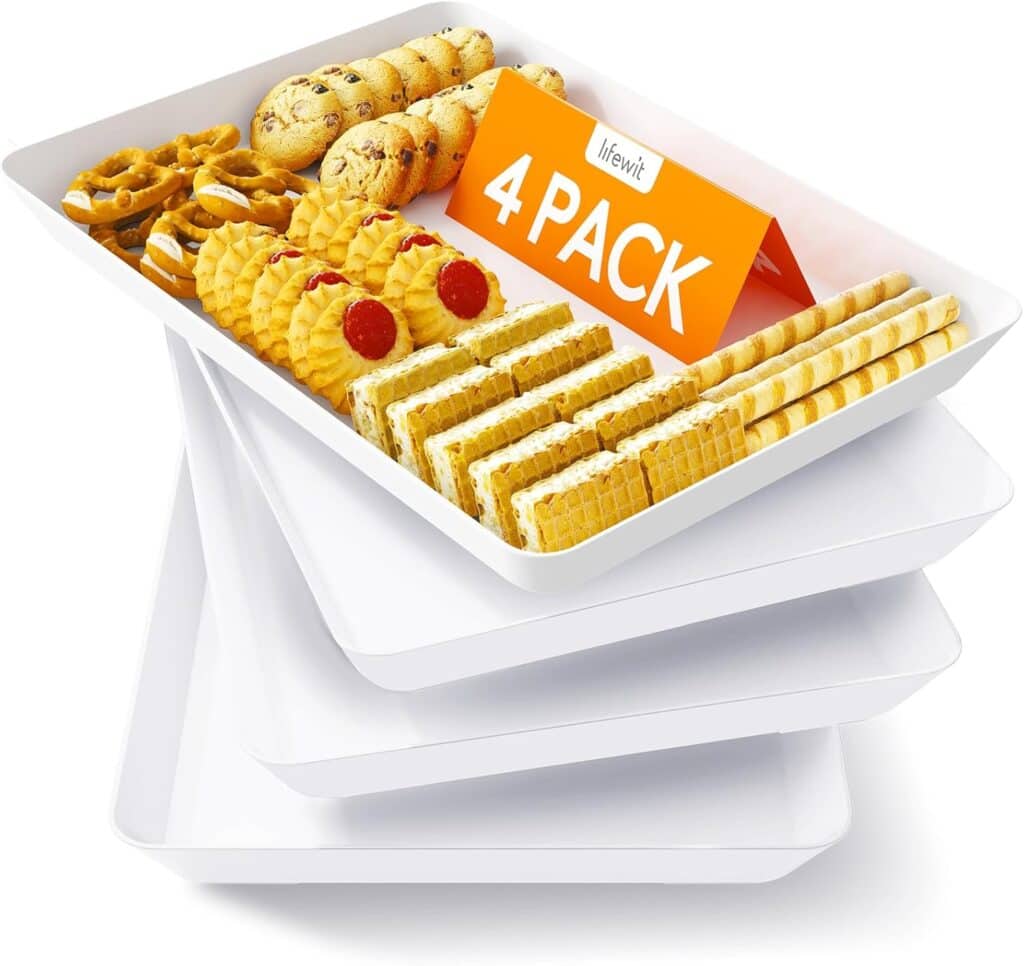 A stack of four white rectangular trays, with the top tray displaying assorted cookies, wafers, and pastries, along with a sign that reads "4 PACK.