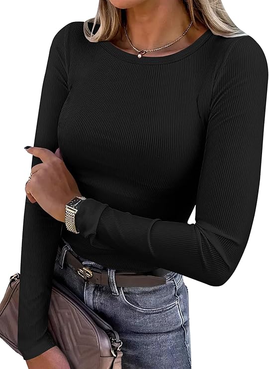 Woman wearing a fitted Rib Knit Top—this women’s long sleeve style in black pairs with light blue jeans, a wristwatch, and a taupe quilted clutch. Her nails are painted black and her loose, light hair frames her look beautifully.