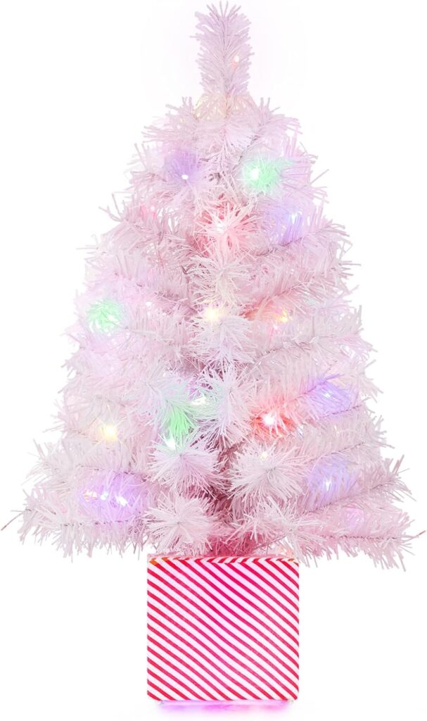 A small white artificial Christmas tree with multicolored lights, standing in a red and white striped box base.