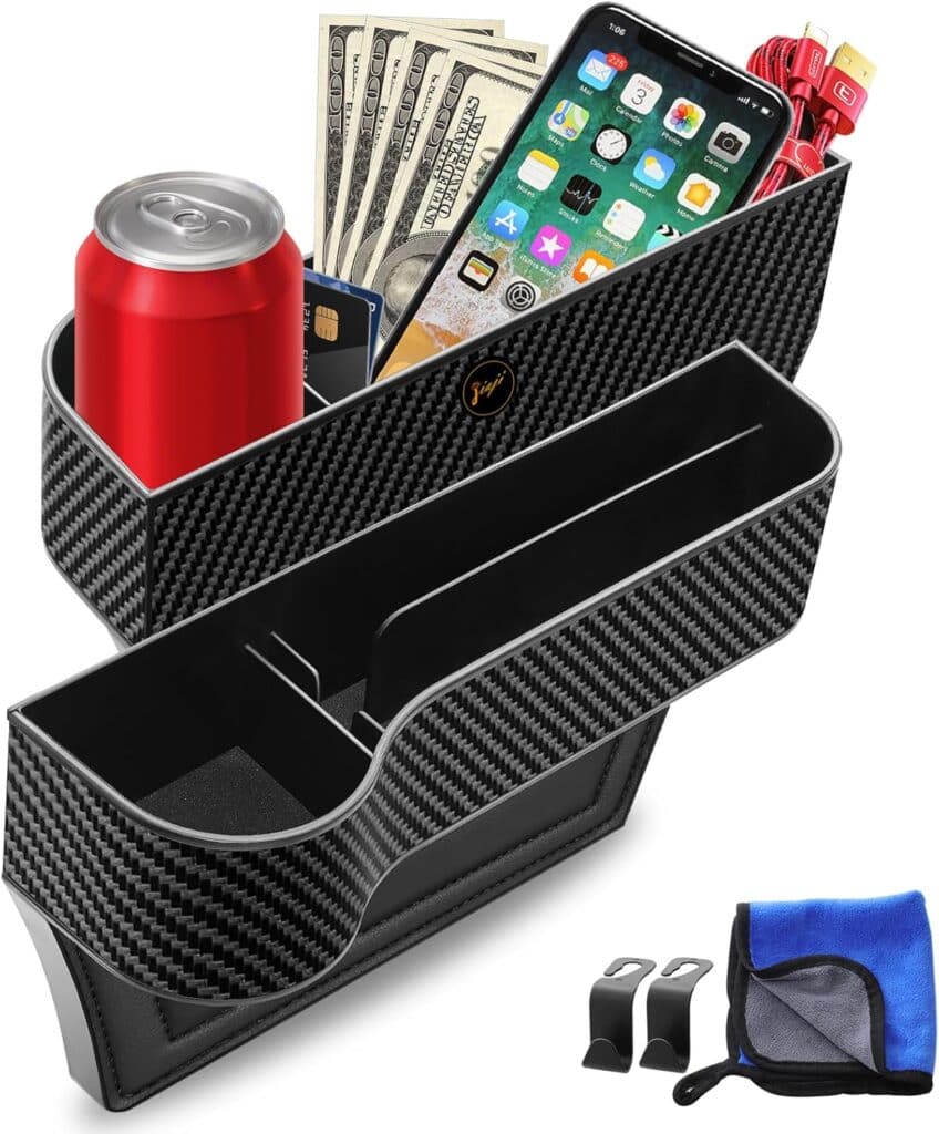 A black carbon-fiber patterned car seat organizer holding a soda can, smartphone, cash, red cables, and cards. Two clips and a blue cleaning cloth are placed beside the organizer.