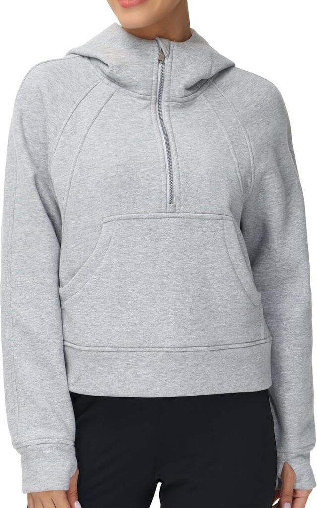 A woman wearing a light gray hooded sweatshirt with a front zipper and kangaroo pocket, paired with black pants. The image is cropped just above her nose.