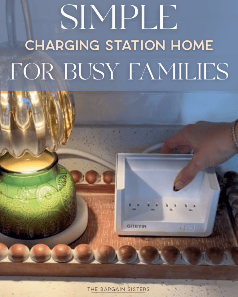 A hand places a white GITRYIN charging station home on a wooden tray beside a green lamp with a gold shade. Text overlay reads: "Simple charging station home for busy families.