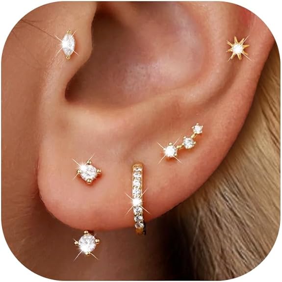 A close-up of an ear adorned with multiple gold and diamond earrings, including studs, a small hoop, and various sparkling designs along the lobe and cartilage.