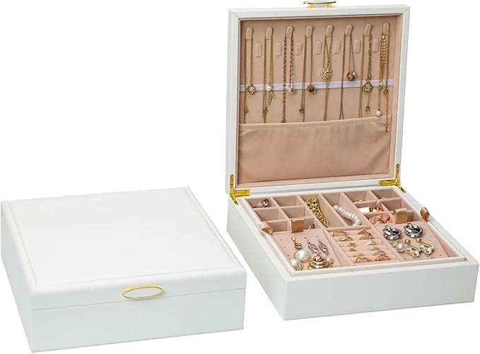 A white jewelry box with a gold handle is shown closed and open. The open box reveals organized compartments holding rings, earrings, and necklaces against a soft beige interior.