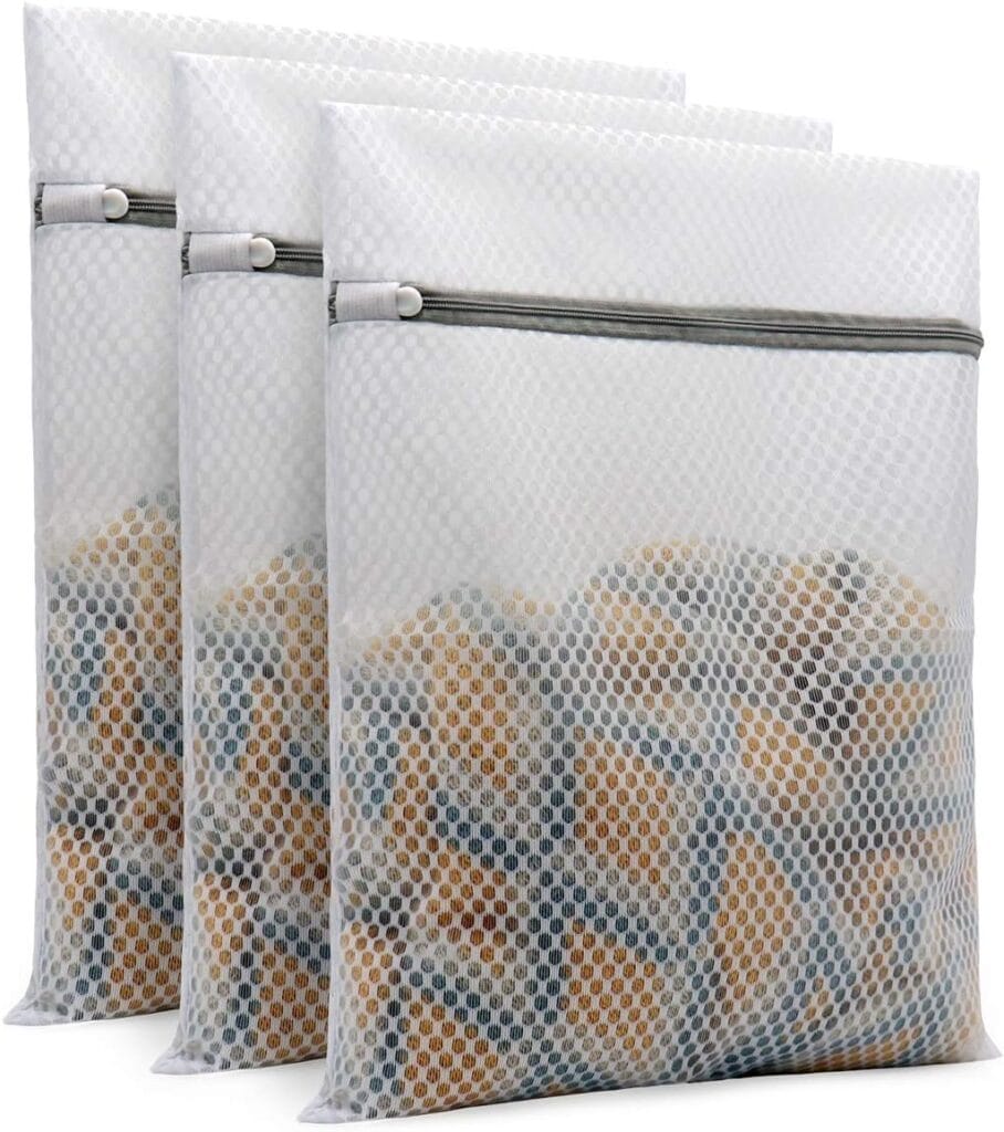 Three white mesh laundry bags with zippers, each filled with clothing and standing upright in a row. The bags are made of a textured, semi-transparent material.