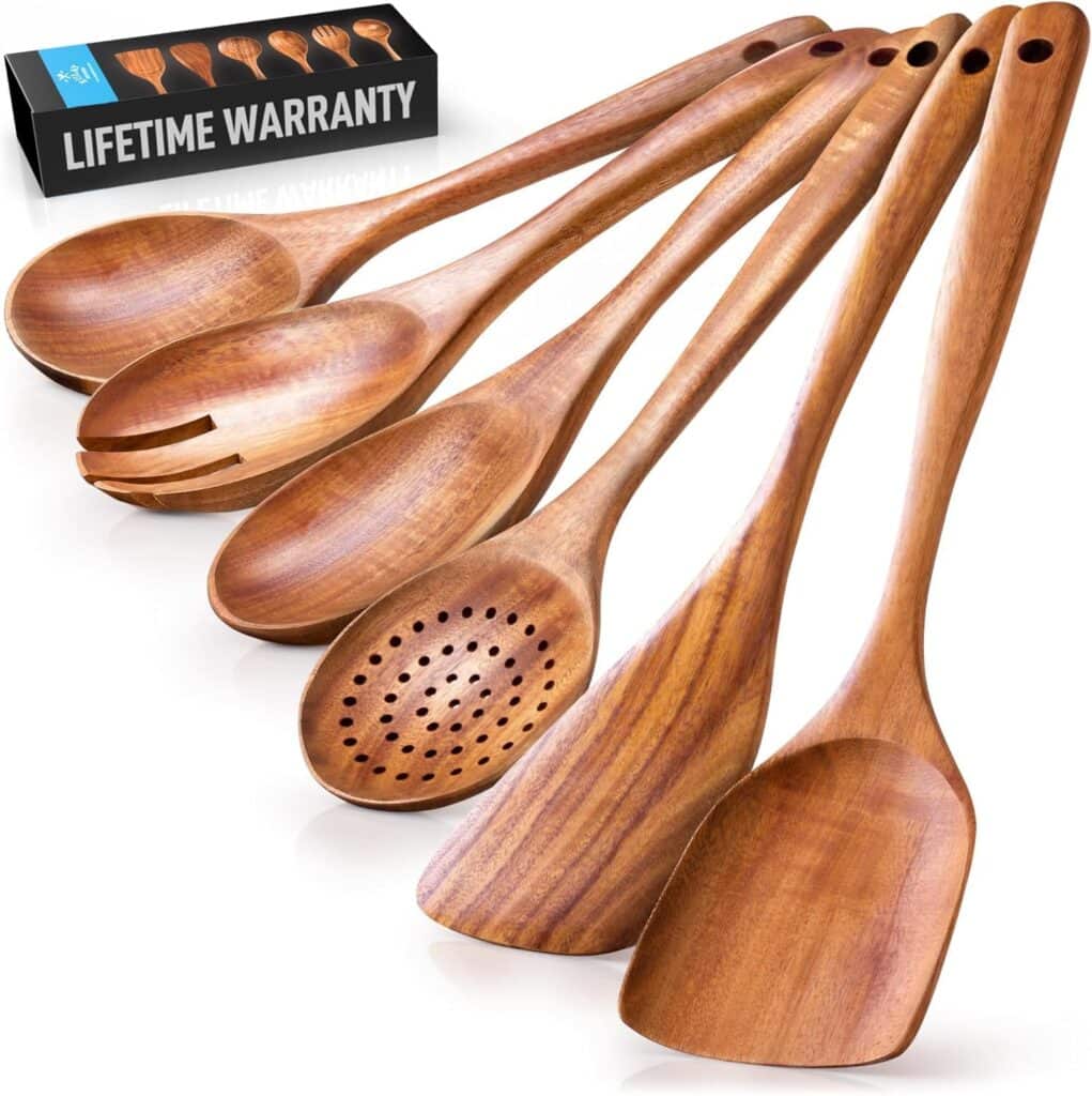 Six wooden kitchen utensils, including spoons, slotted spoon, and spatula, are arranged in a row. A box in the background displays "Lifetime Warranty" with utensil illustrations on it.