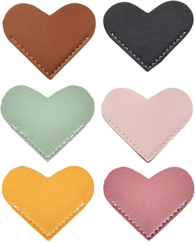 Six heart-shaped leather patches in brown, black, light green, light pink, yellow, and mauve, each with visible stitching around the edges, arranged in two rows of three.
