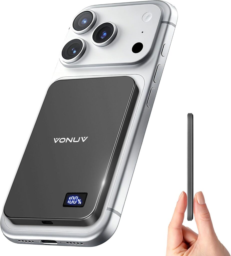 A slim black portable charger with a digital display is attached to the back of a silver smartphone. A hand holds the thin charger upright next to the phone, showing its compact design. The phone has three rear cameras.