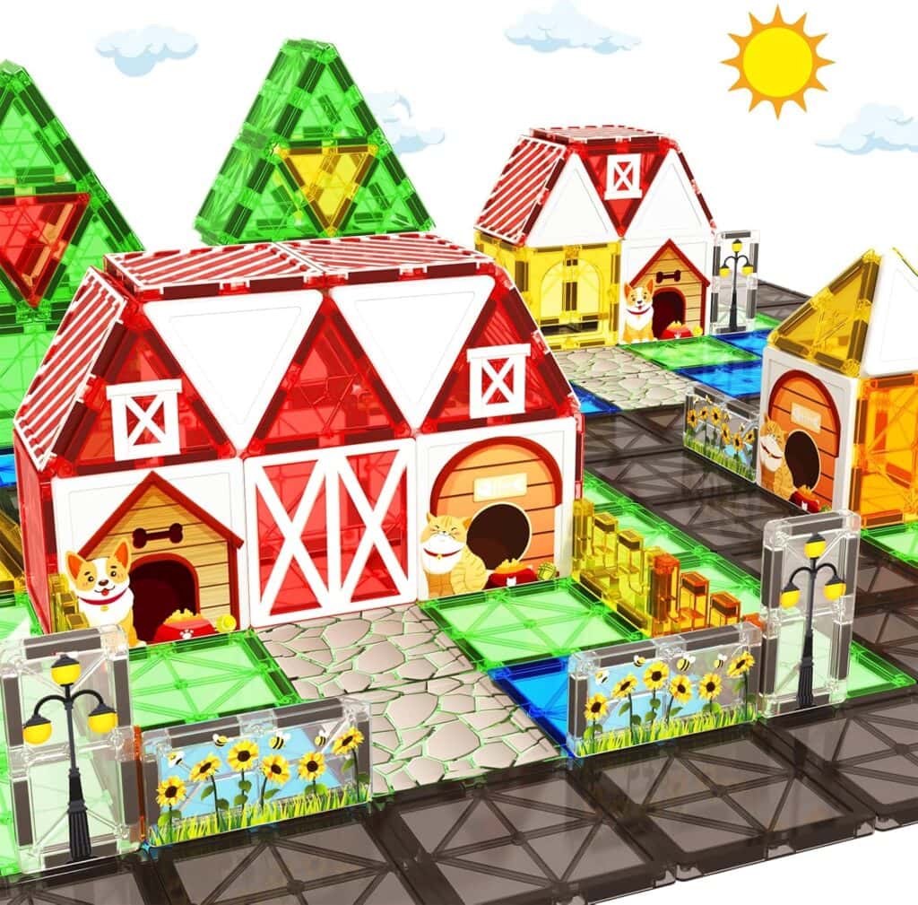 A colorful toy farm set made of magnetic tiles features barns, small houses, a doghouse, fences, sunflowers, street lamps, and green fields under a sunny sky with clouds.