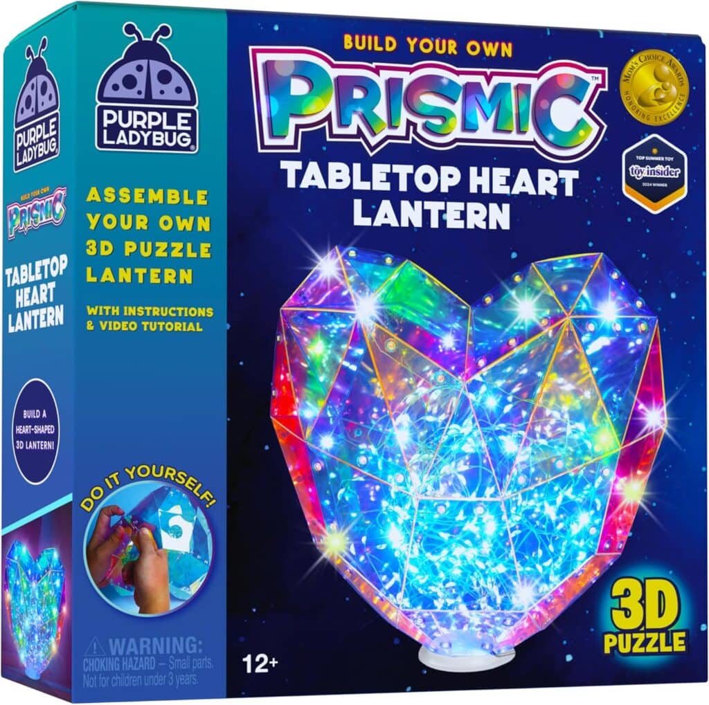 A colorful box for the "Prismic Tabletop Heart Lantern" 3D puzzle kit by Purple Ladybug, featuring a glowing, multicolored heart-shaped lantern and instructions for assembly. For ages 12 and up.