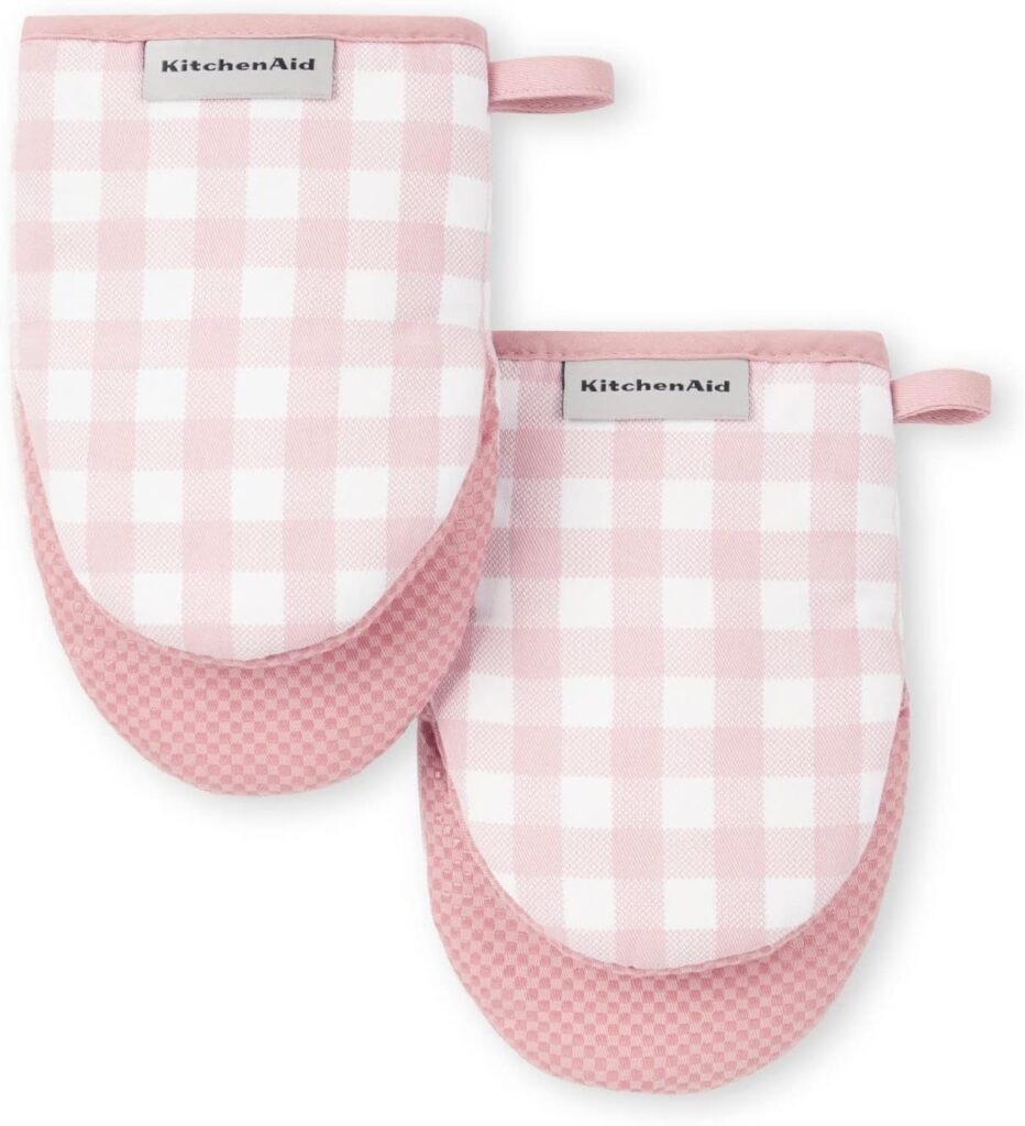 Two pink and white checkered KitchenAid oven mitts with a hanging loop, placed side by side on a white background. The lower portion of each mitt has a textured pink grip.