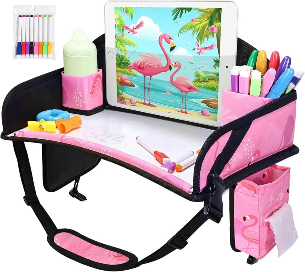 A pink portable tray for kids features storage pockets, marker holders, a bottle holder, and a tablet displaying flamingos. Various colorful markers and a toy are on the tray and in the side pockets.