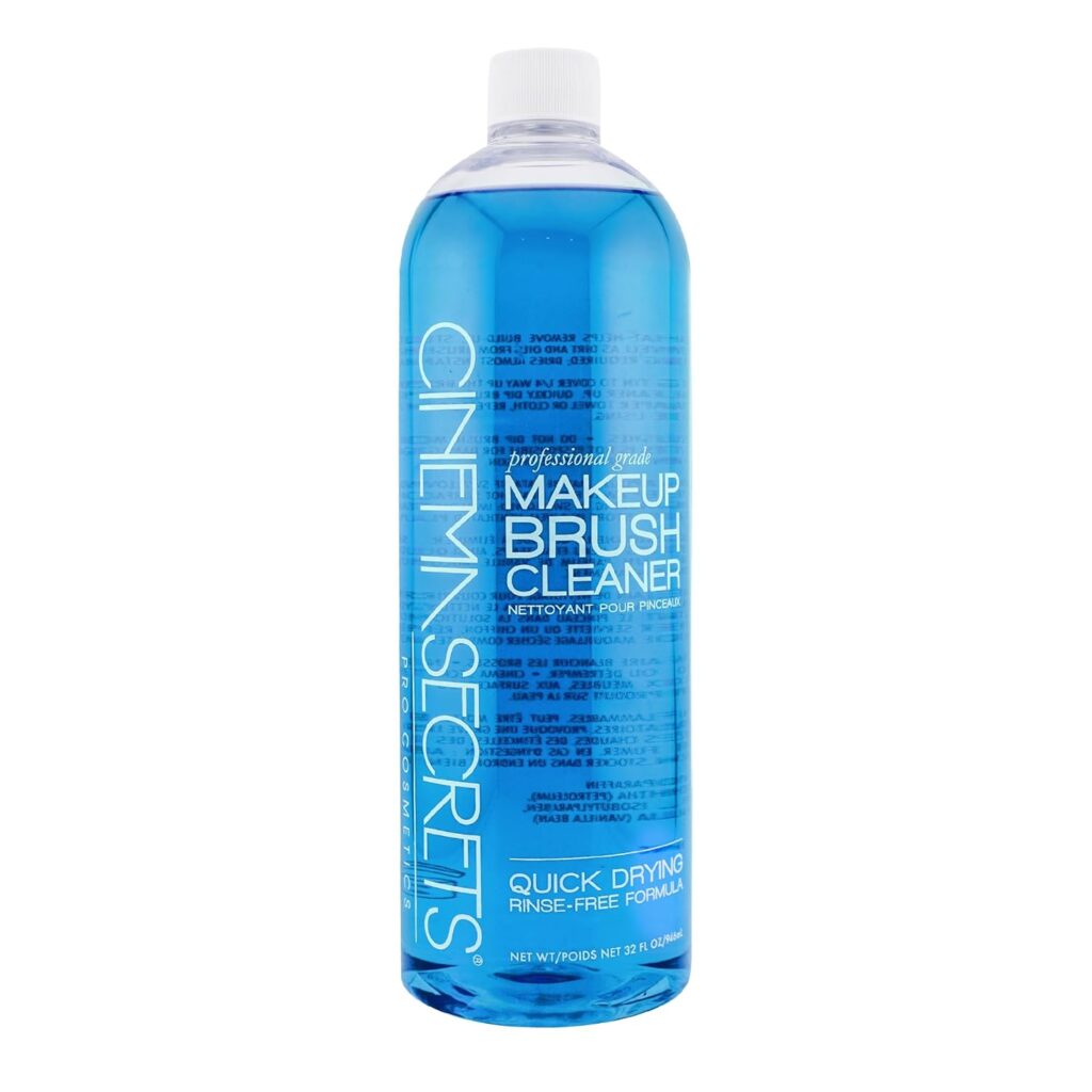 A clear plastic bottle of Cinema Secrets Professional Grade Makeup Brush Cleaner filled with blue liquid, featuring white text and a white cap. The label highlights it as quick drying and rinse-free.